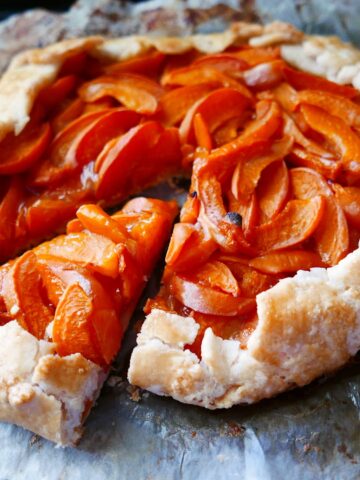 apricot gluten free galette on a baking sheet with one piece cut
