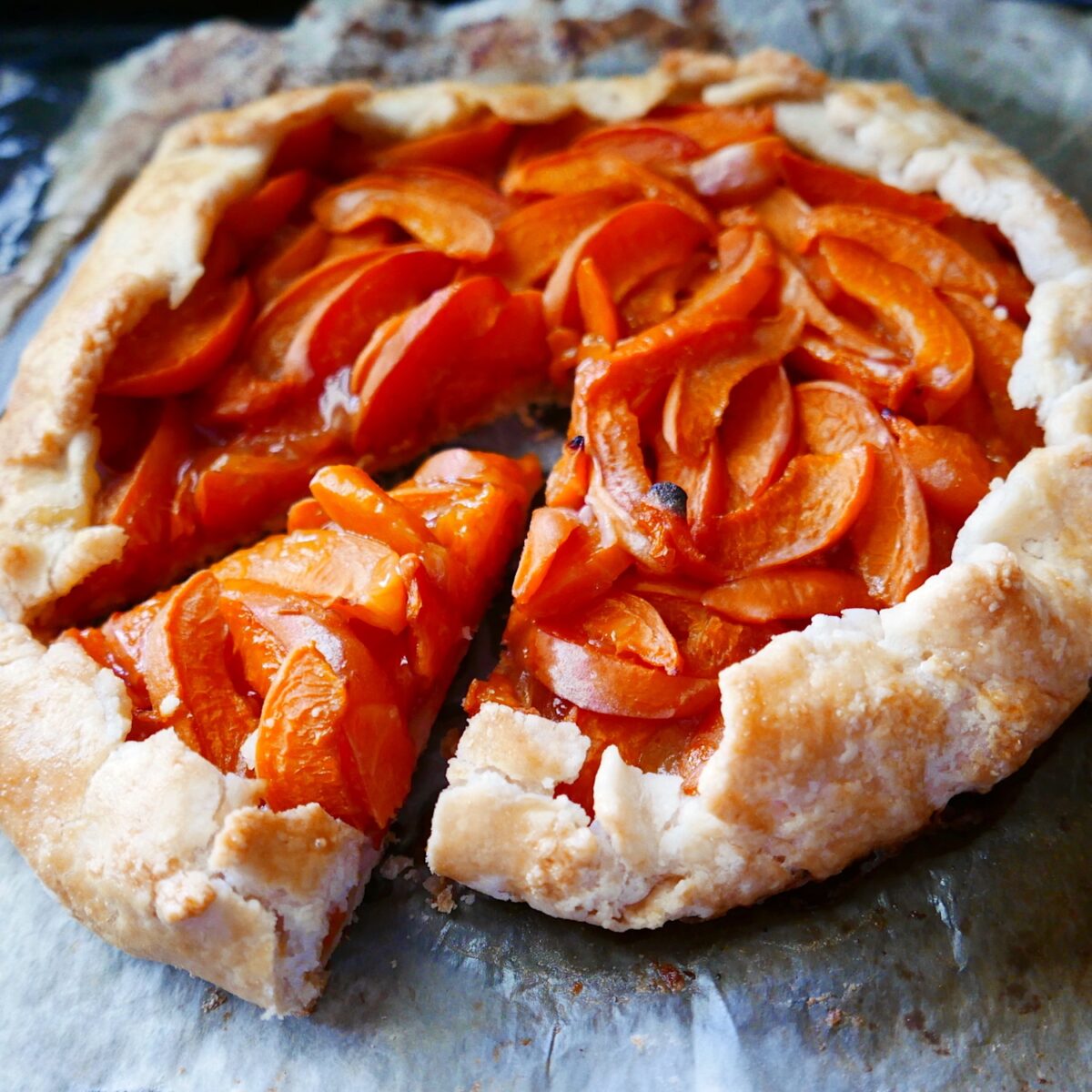 apricot gluten free galette on a baking sheet with one piece cut out. 