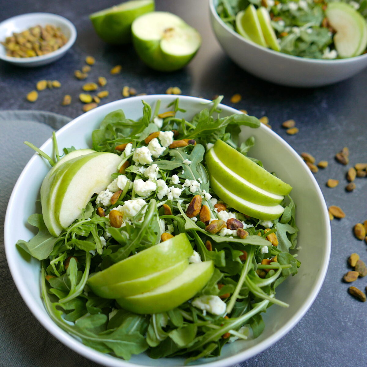 apple gorgonzola salad in a large bowl with a sliced apple in the background. 