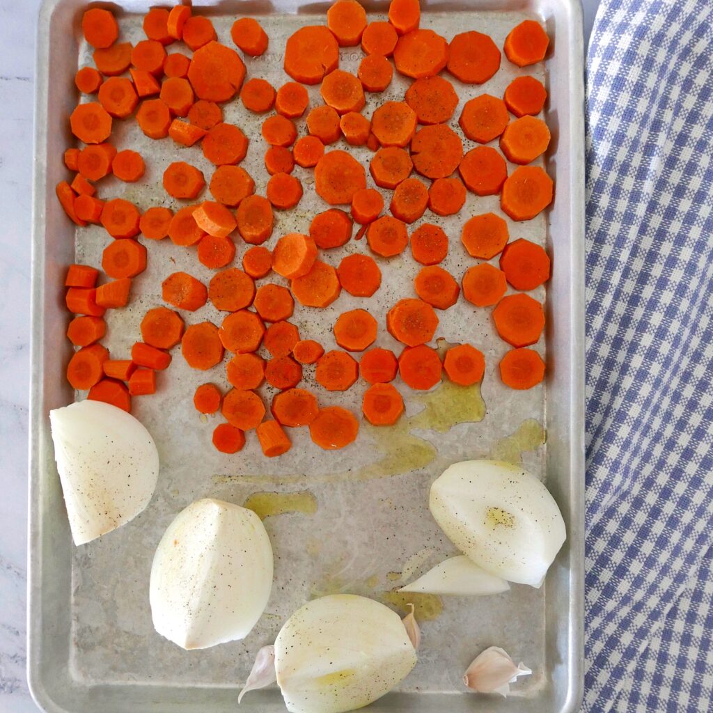 carrots, onions, and garlic on a baking sheet