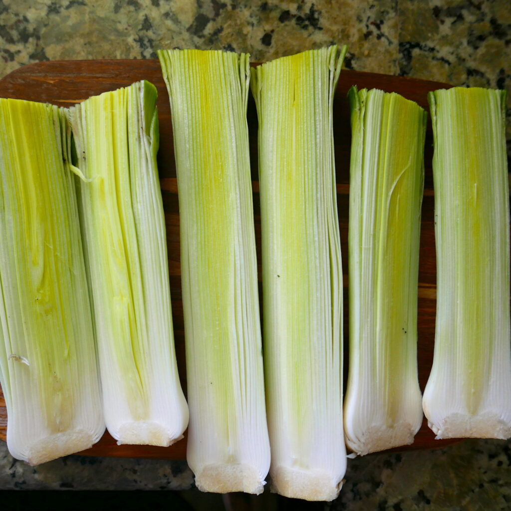 cut leeks resting on a wooden cutting board