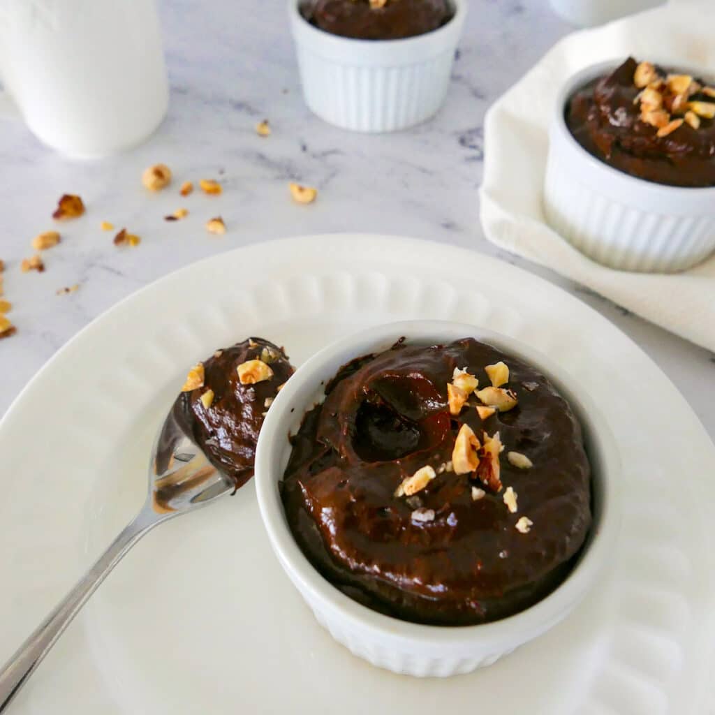 chocolate avocado pudding in a white cup with spoon