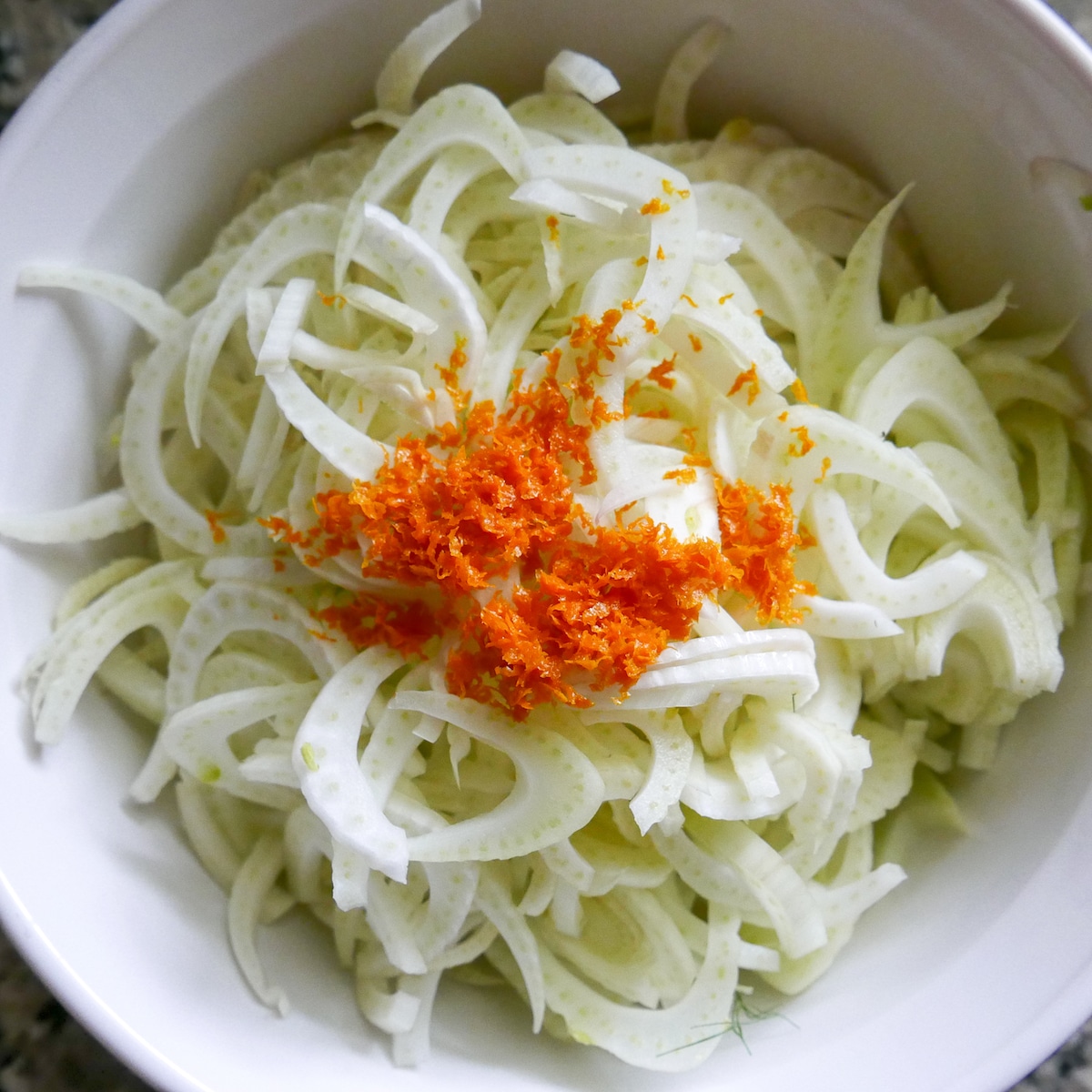 shaved fennel in a mixing bowl with orange zest