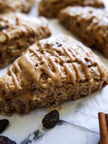 cinnamon raisin scones with cinnamon glaze arranged on parchment paper.