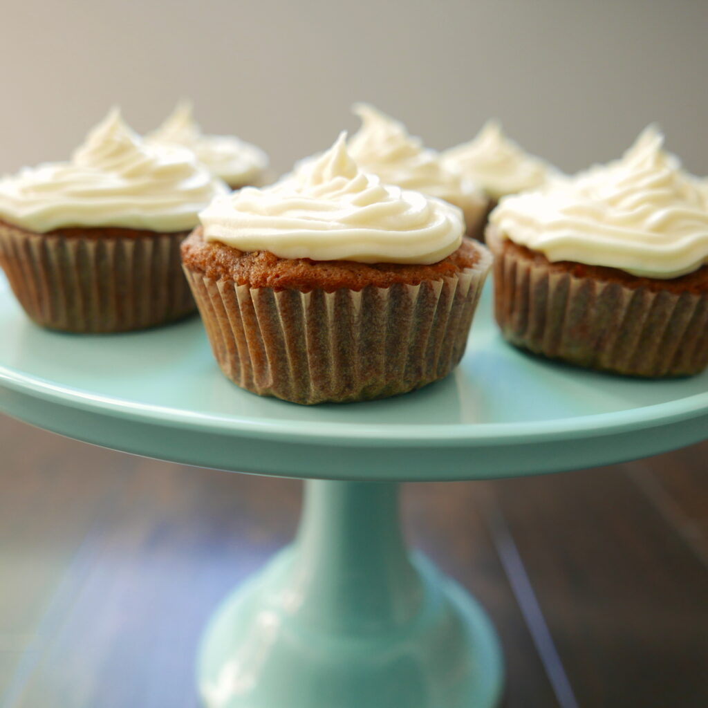 carrot cake cupcakes displayed on a teal cake stand