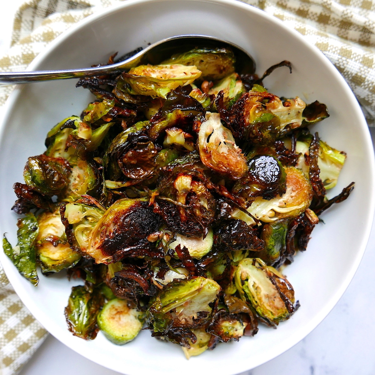 vegan roasted brussel sprouts with garlic in a white bowl with spoon.