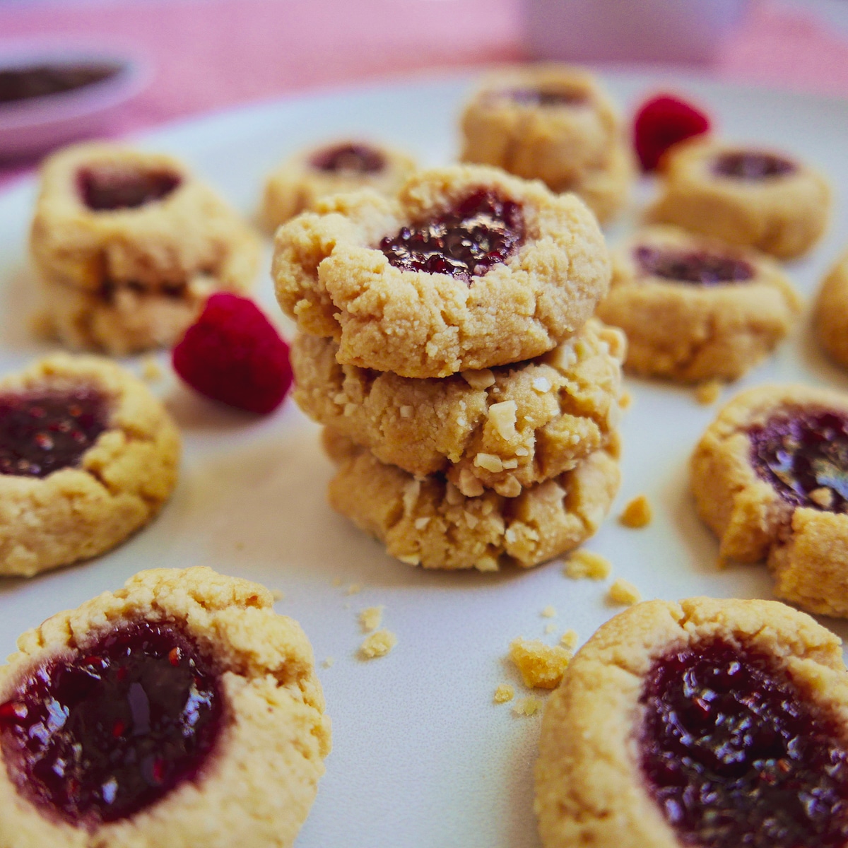 thumbprint cookies arranged on a white platter with cookie crumbs.