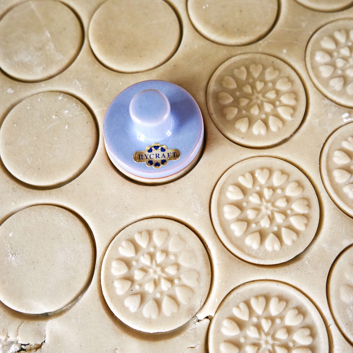 shortbread cookies being pressed with stamp.