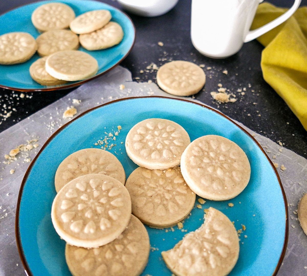 Cookies arranged on two blue plates with parchment and crumbs scattered around.