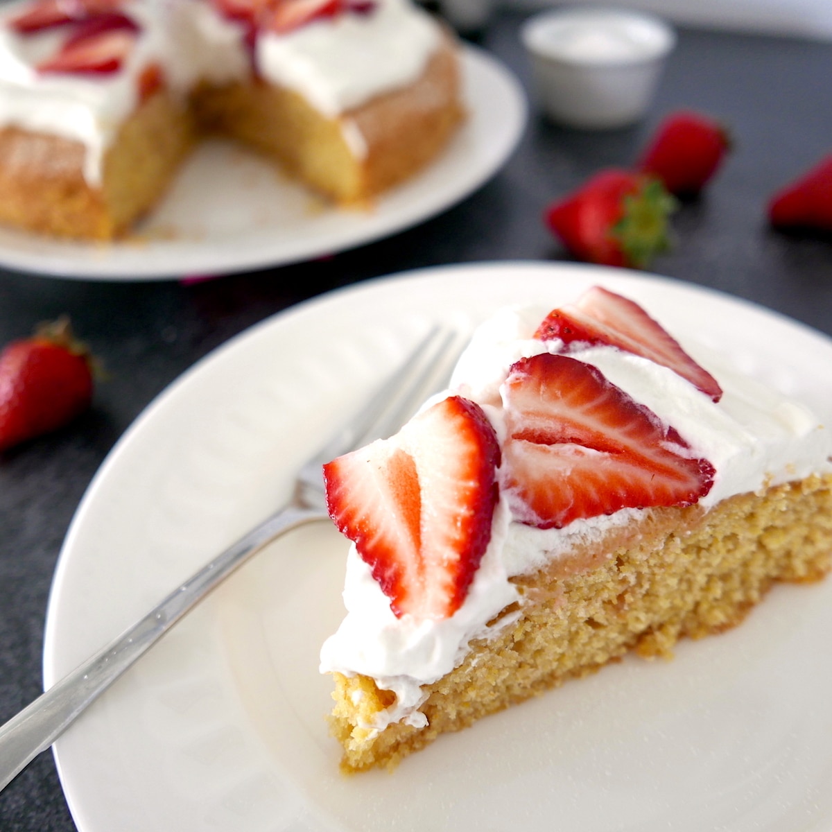one slice of strawberry cornmeal cake on a white plate with fork.