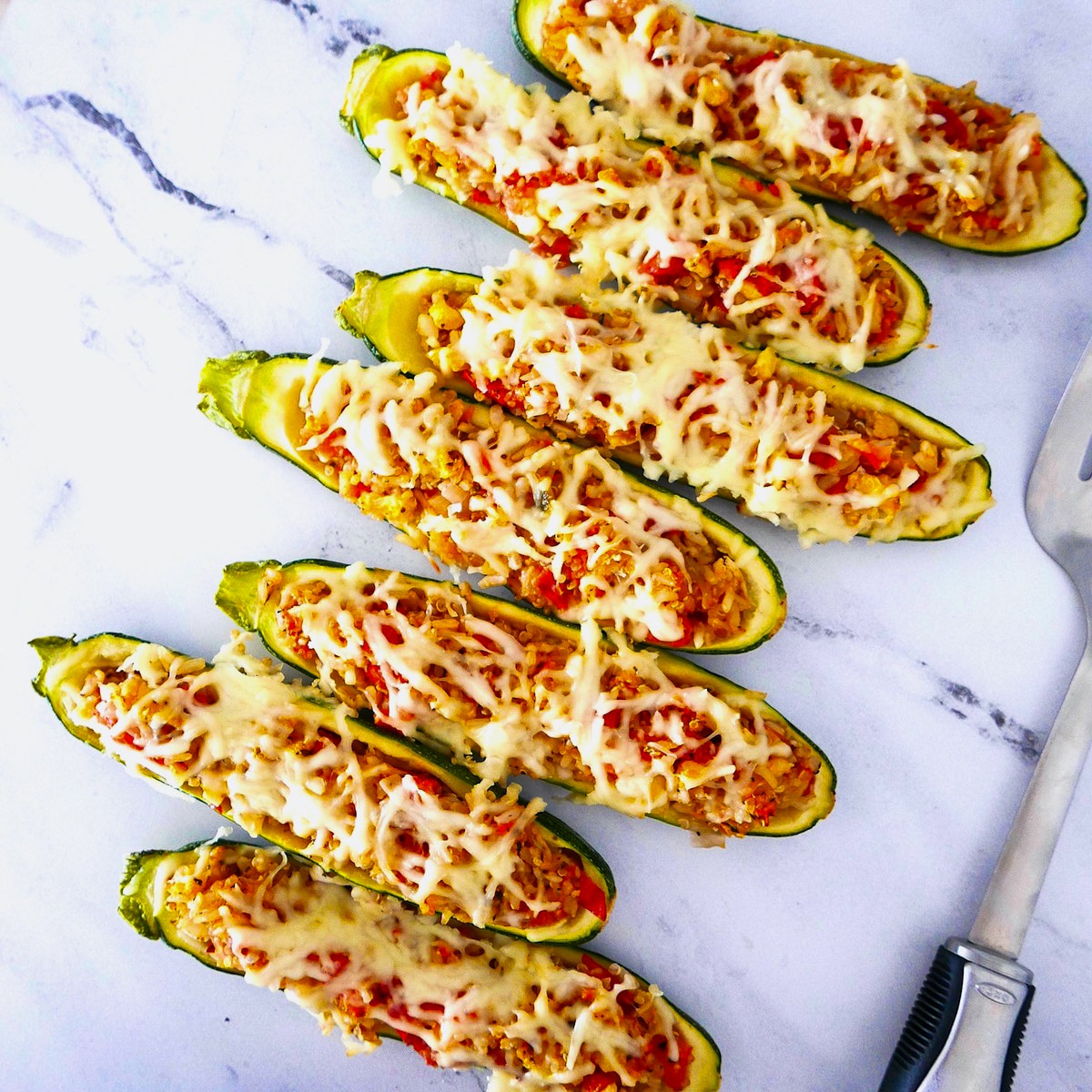 rice-stuffed-zucchini-boats.jpg seven rice stuffed zucchini boats on a marble counter top