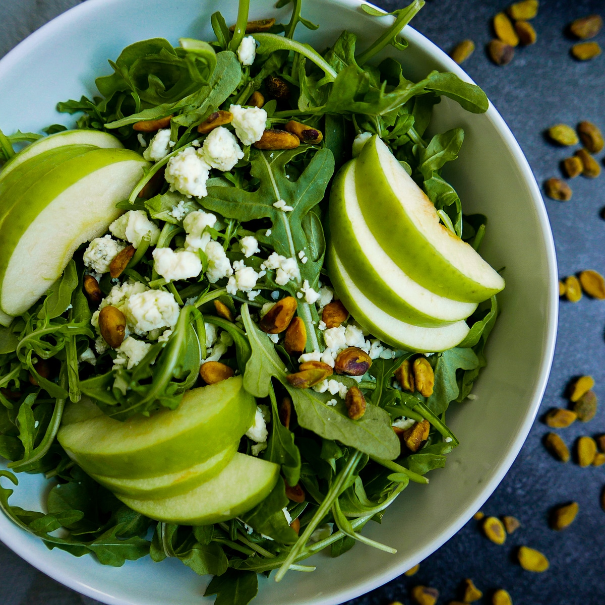 harvest apple salad with pistachios and blue cheese in large white bowl