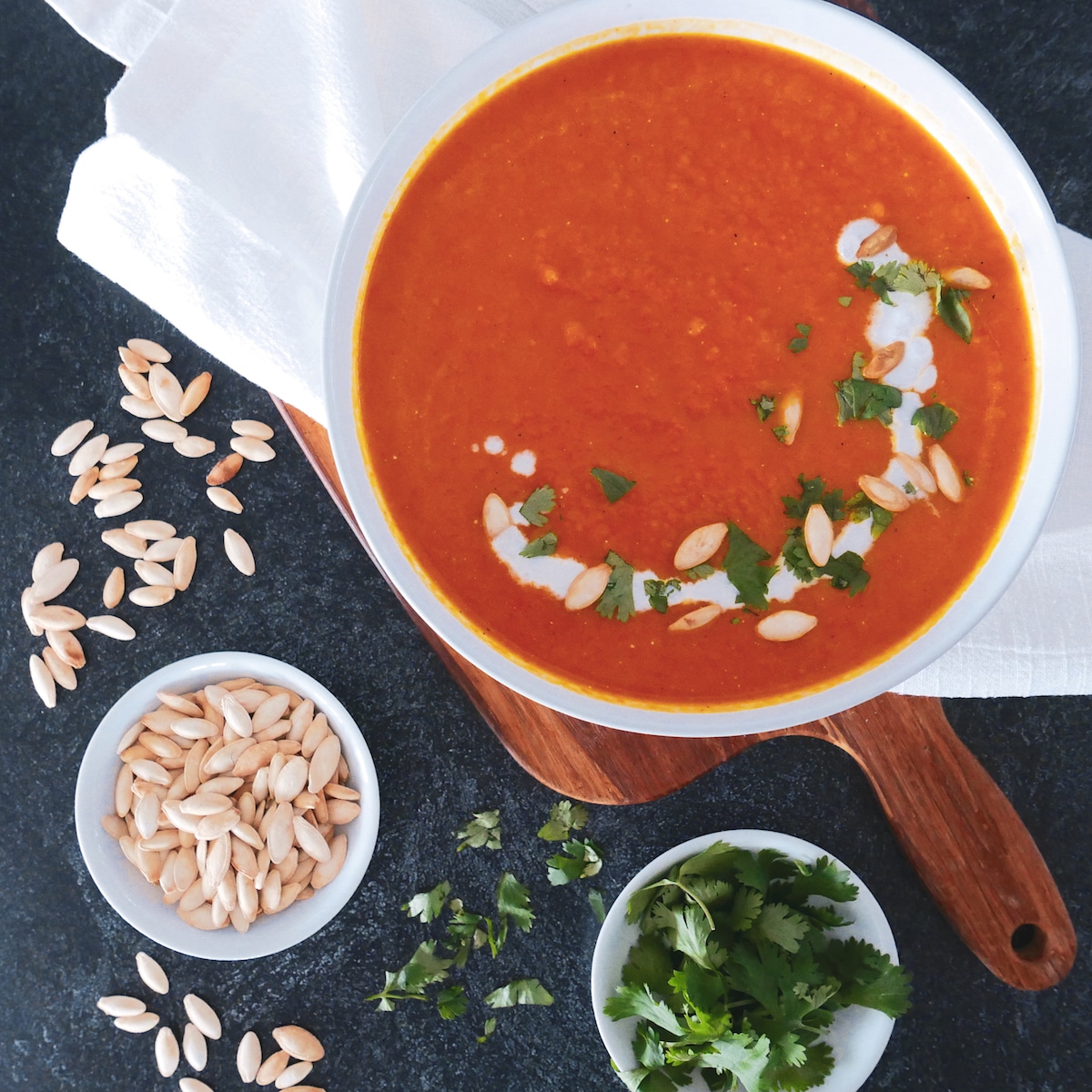 Bowl of soup resting on a napkin-lined cutting board and garnished with cilantro. 