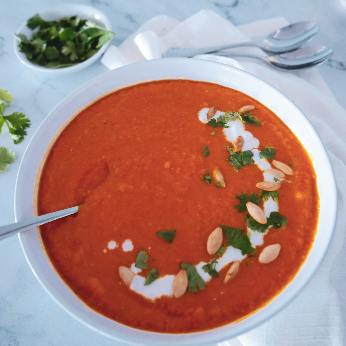 butternut squash carrot ginger soup with spoon squash carrot ginger soup in bowl with spoon and cilantro