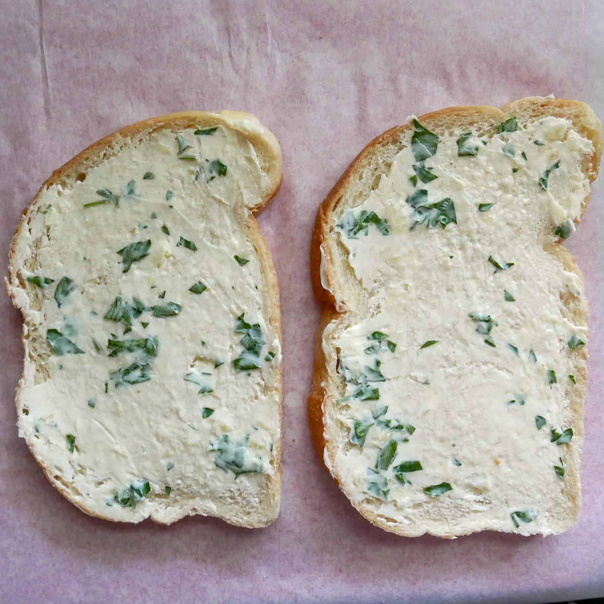 Garlic butter spread on two slices of sourdough bread on a cutting board.