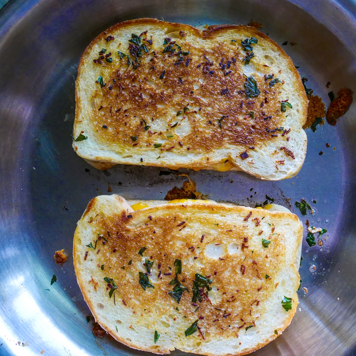 Grilled cheese being cooked until golden brown in a skillet.