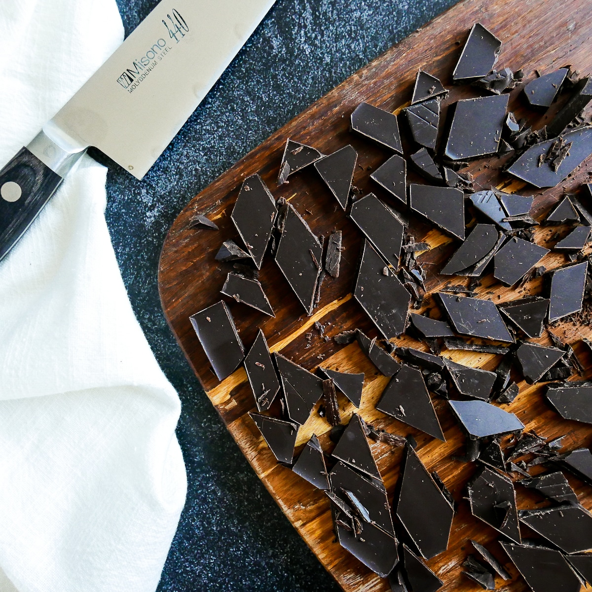 chopped dark chocolate on a cutting board with knife.