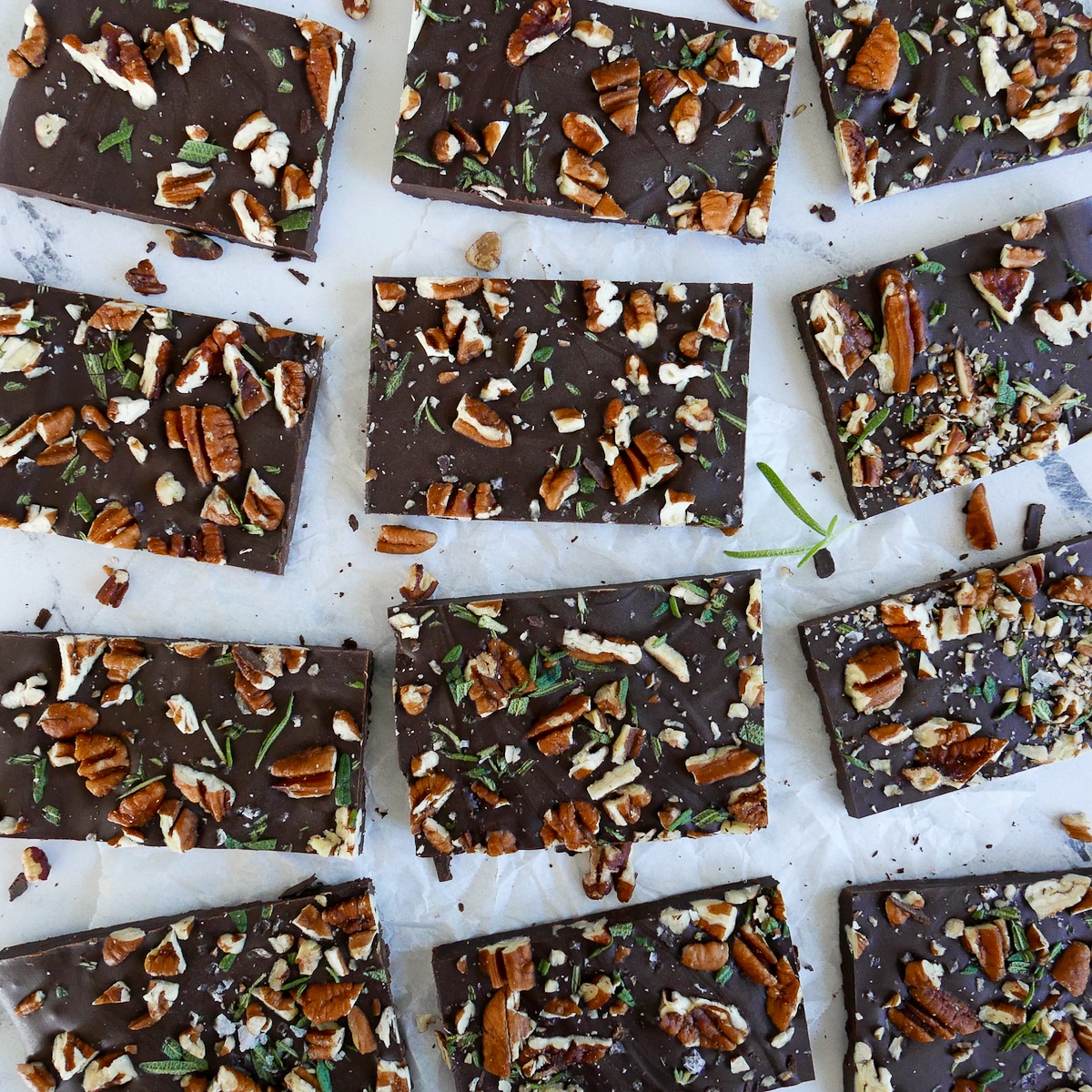 chocolate-pecan-bark-on-parchment.jpg chocolate pecan rosemary bark cut into squares and arranged on parchment