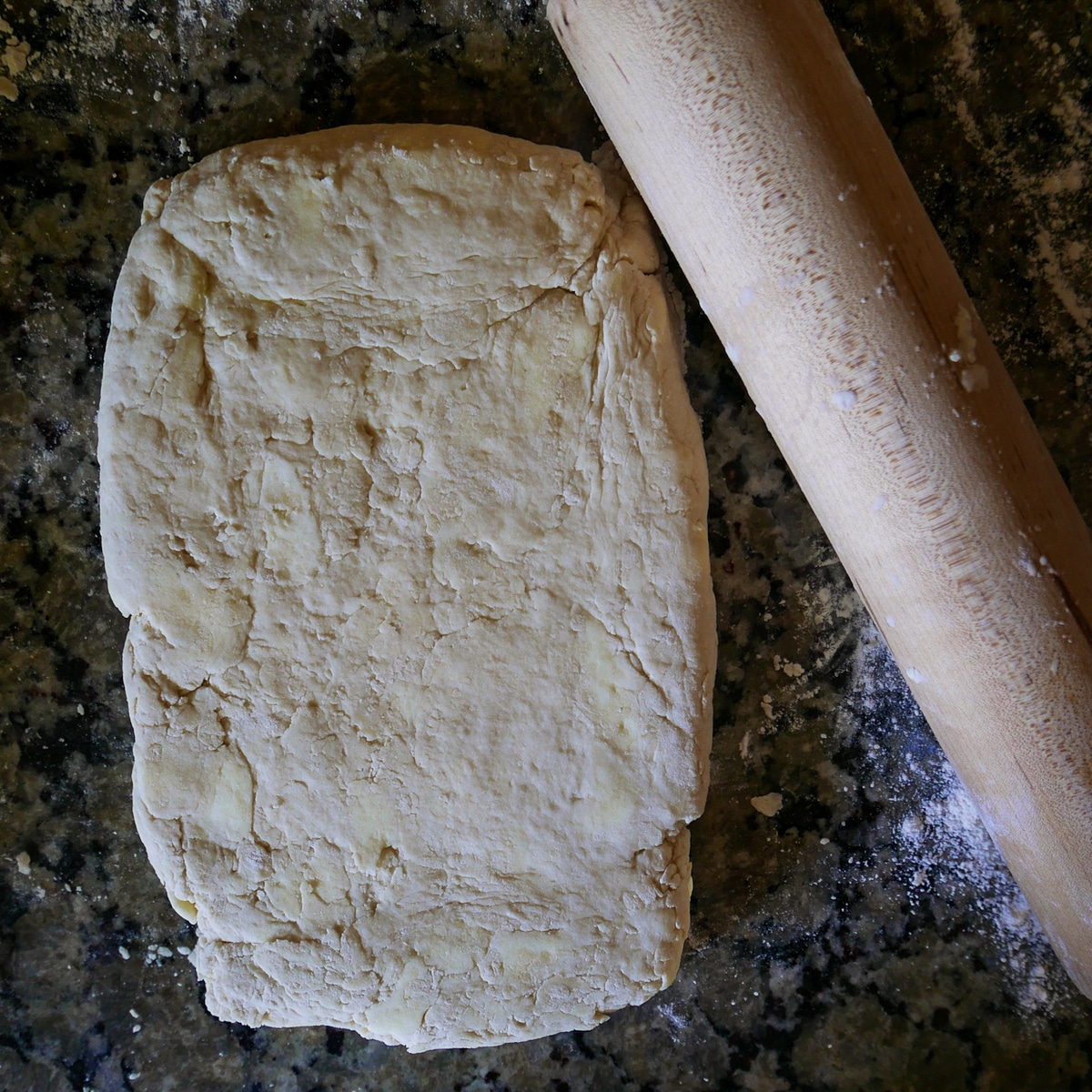 Biscuit dough being rolled out with rolling pin.