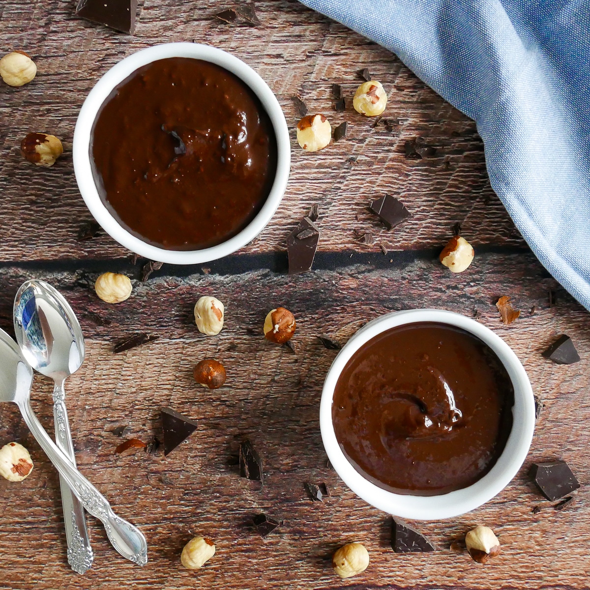 two cups of nutella two cups of vegan nutella with spoons on wooden table