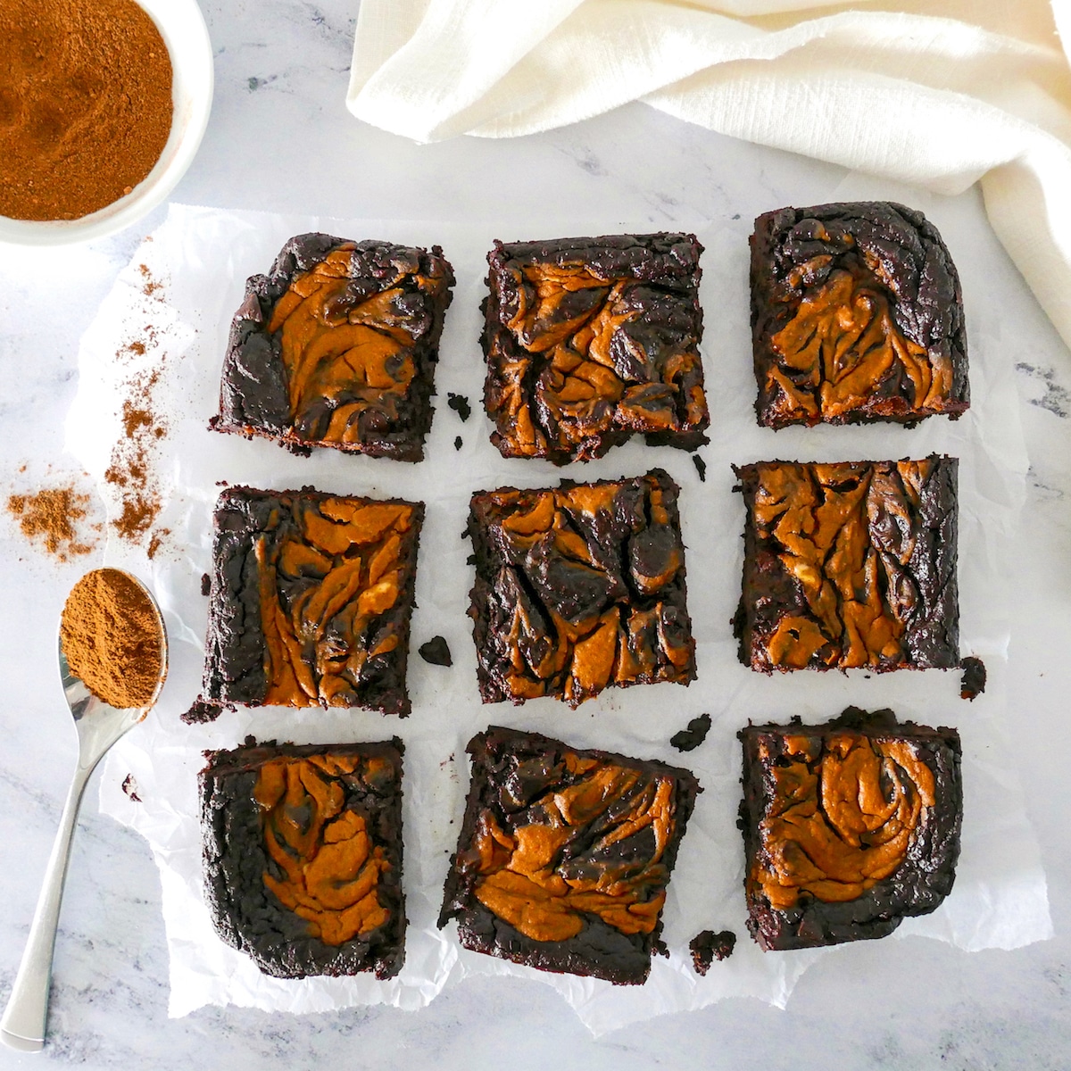 Healthy pumpkin brownies cut into nine pieces and arranged on parchment paper.