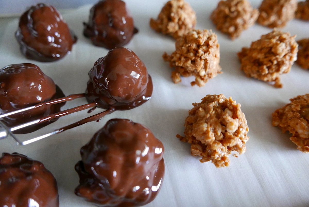 peanut butter balls being dipped into chocolate.