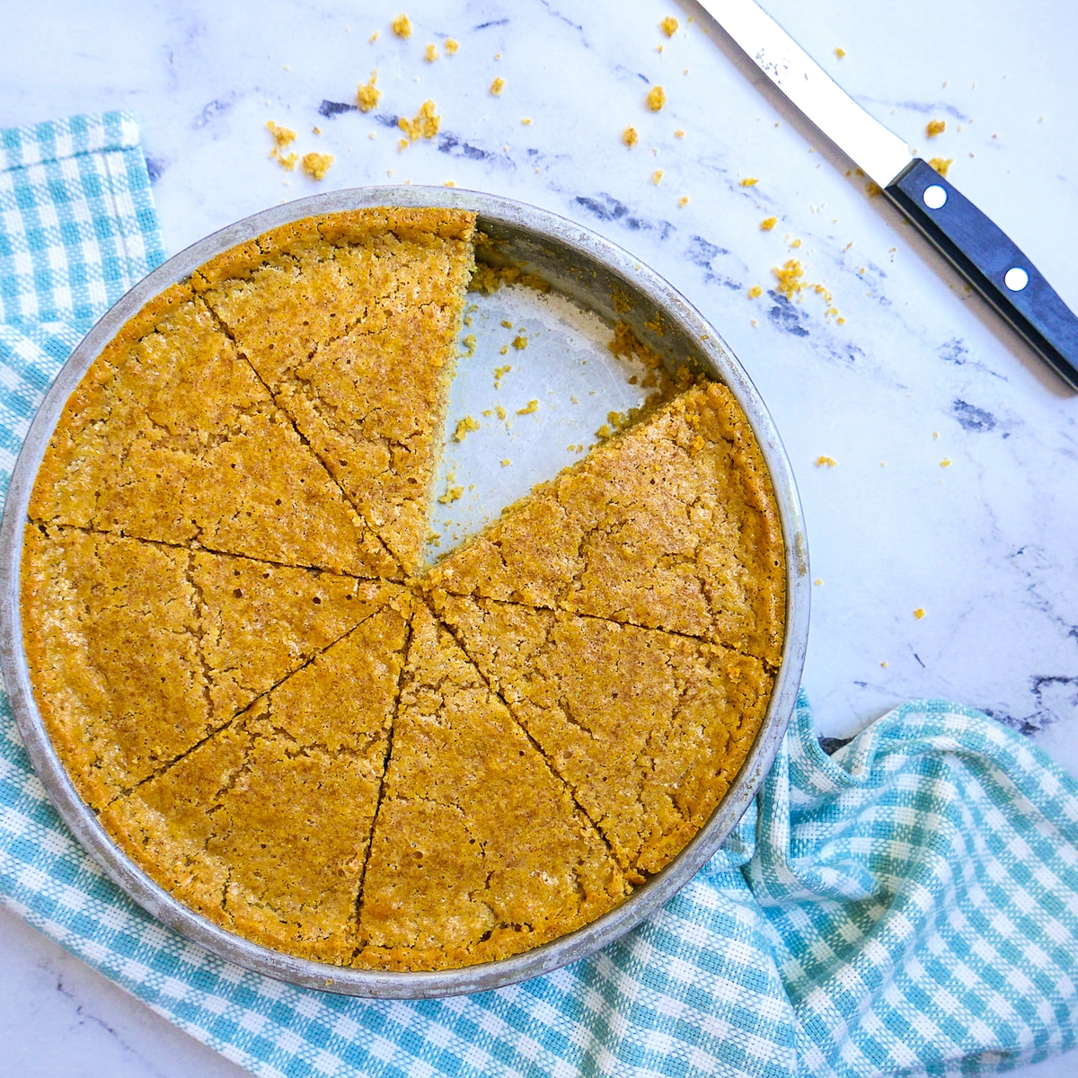 sourdough cornbread in a round pan with one slice missing.