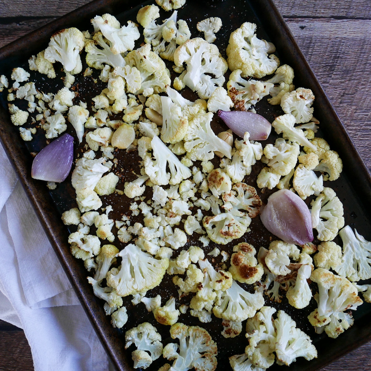 cauliflower-and-shallots-on-baking-sheet.jpg roasted shallots, cauliflower, and garlic on a baking sheet.