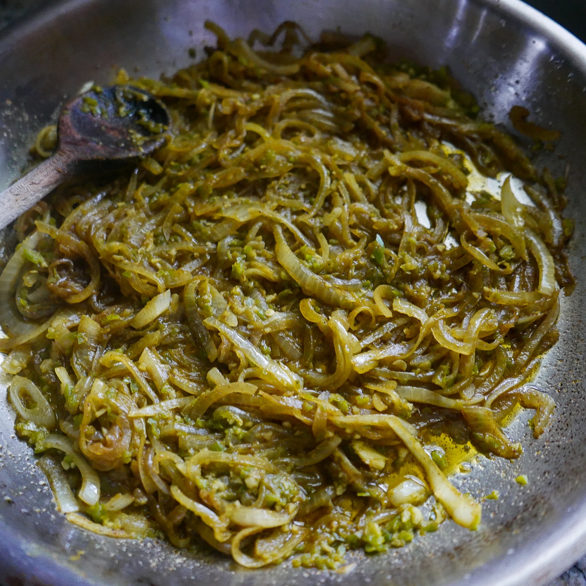 Cooked onions in a skillet with garlic, ginger, jalapeno, and spices.