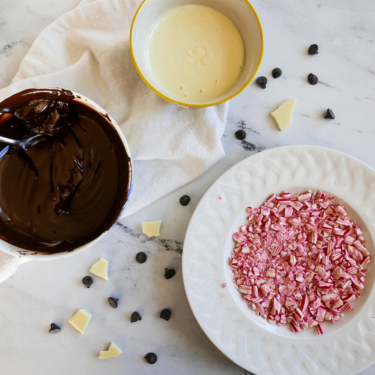 plate of crushed peppermint candy and two bowls of chocolate with spoon.