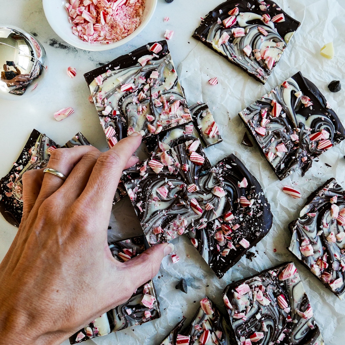 white hand picking up piece of peppermint bark.