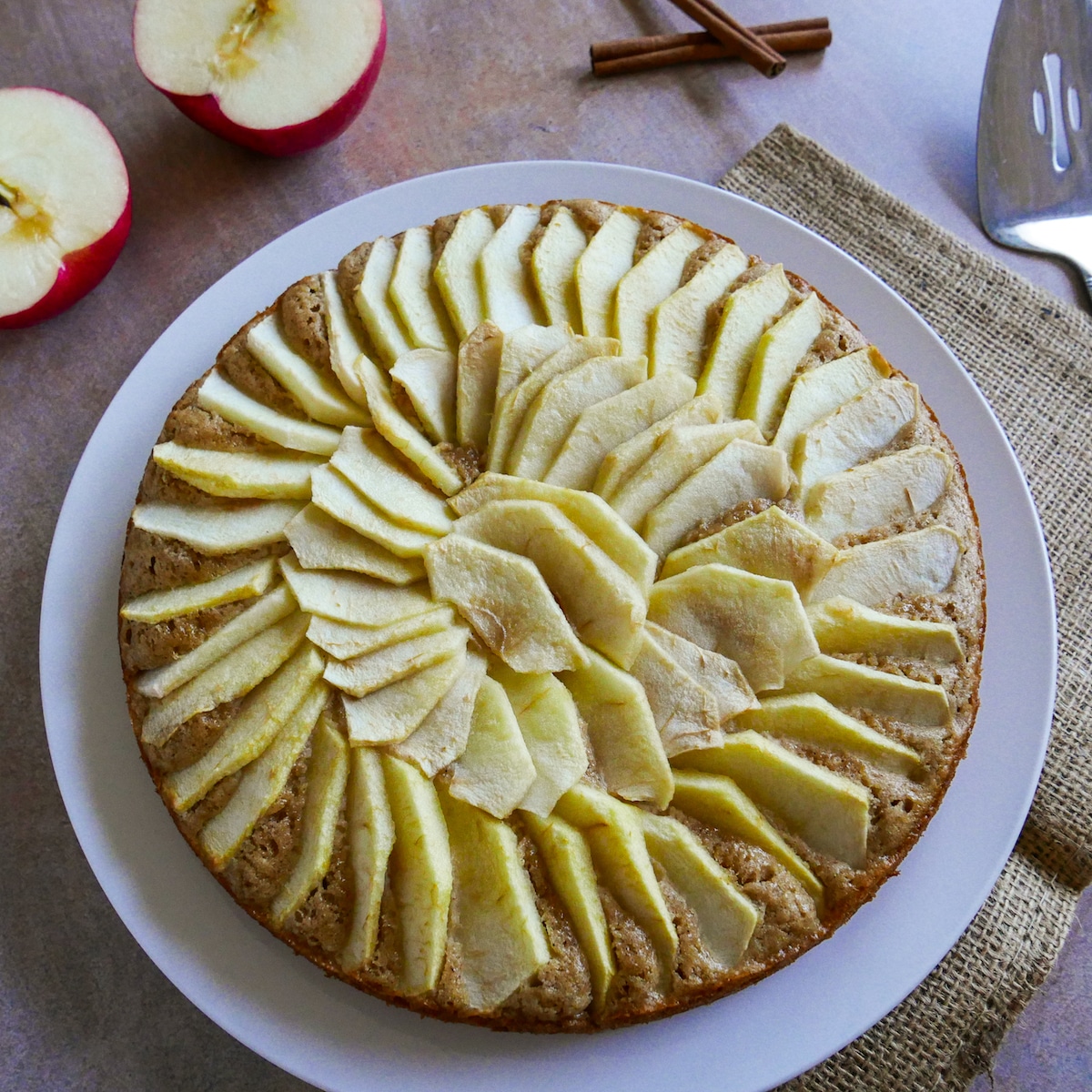 dutch-apple-cake.jpg Apple cake on a white platter with cut apple and pie server in background.