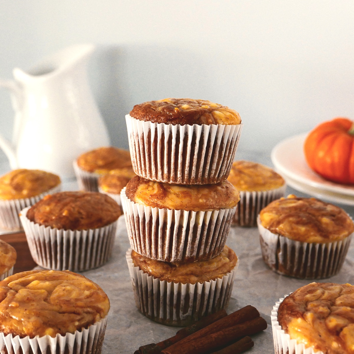 pumpkin muffins arranged on a table with milk pitcher in background.
