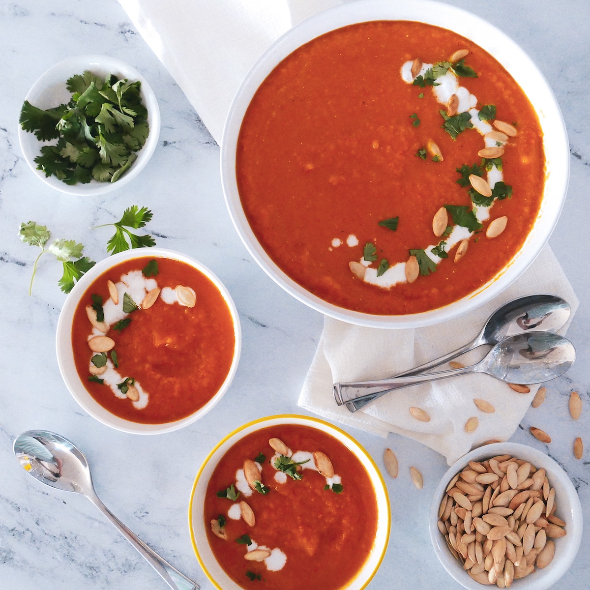 roasted-butternut-squash-carrot-ginger-soup.jpg roasted squash soup in three bowls with white napkin and spoons.