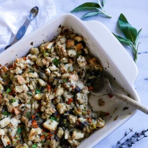 pan of veggie stuffing with wooden spoon and sage