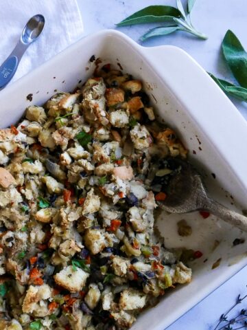 pan of veggie stuffing with wooden spoon and sage