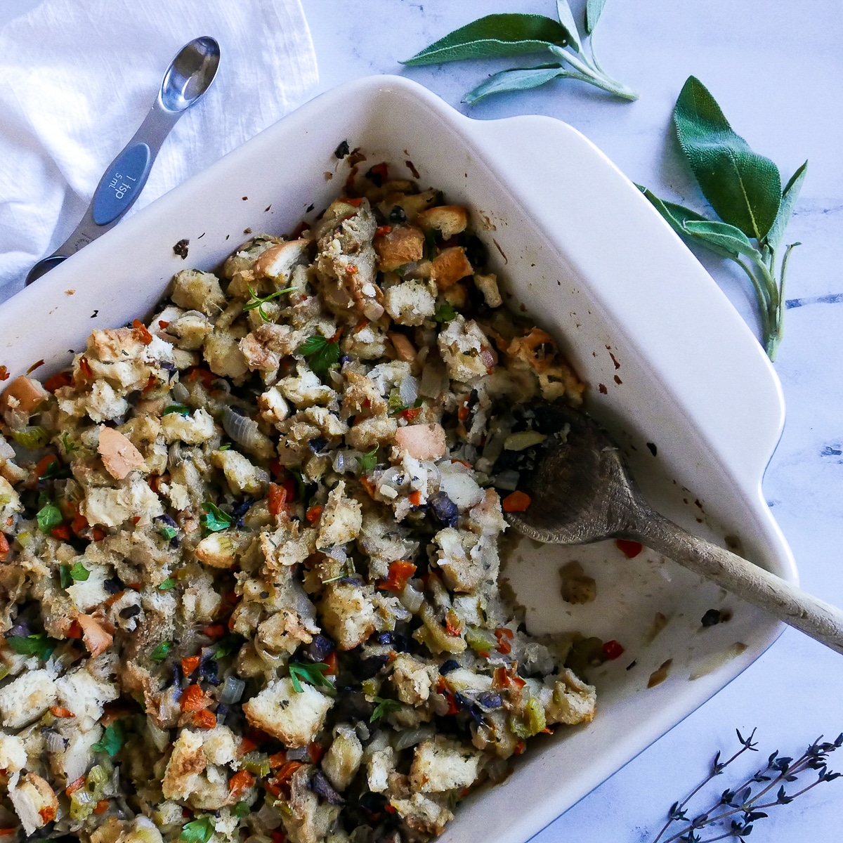 easy-veggie-stuffing-with-mushrooms.jpg Vegetarian stuffing in a baking dish with a wooden spoon and sage next to dish.