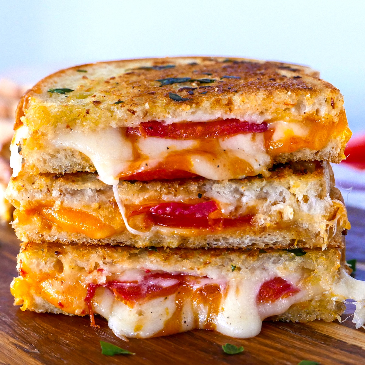 garlic grilled cheese stacked three high on a cutting board.