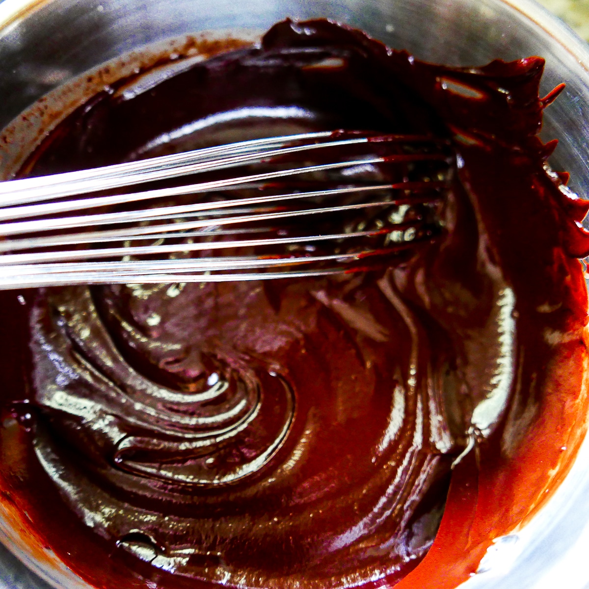 chocolate ganache being whisked in a mixing bowl.