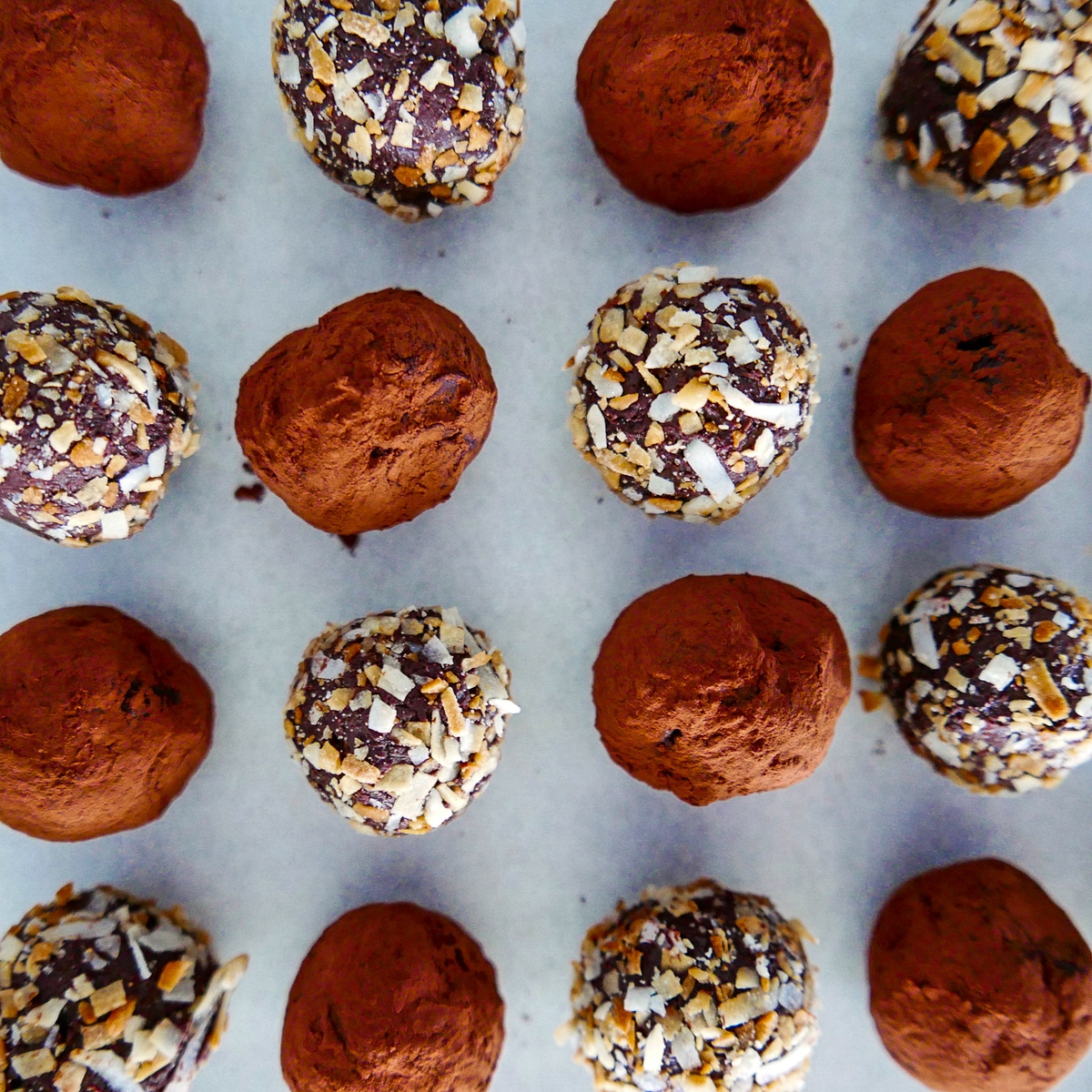 truffles rolled in cocoa powder and toasted coconut arranged on a baking sheet.