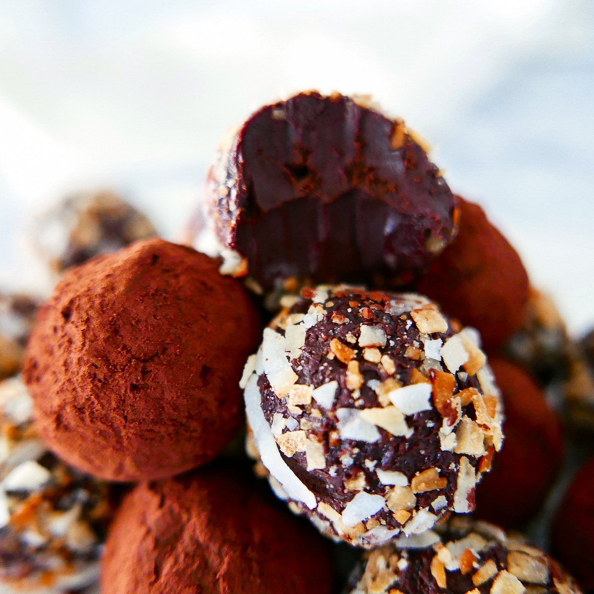 A pile of gluten free truffles with the top one missing a bite.