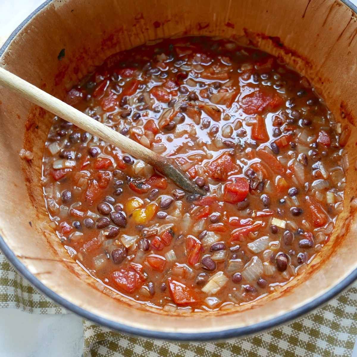 Black bean soup in a large pot with wooden spoon.