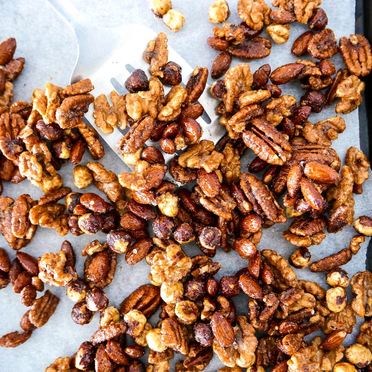 spatula-scooping-up-spiced-nuts.jpg spatula scooping up spiced nuts from baking sheet