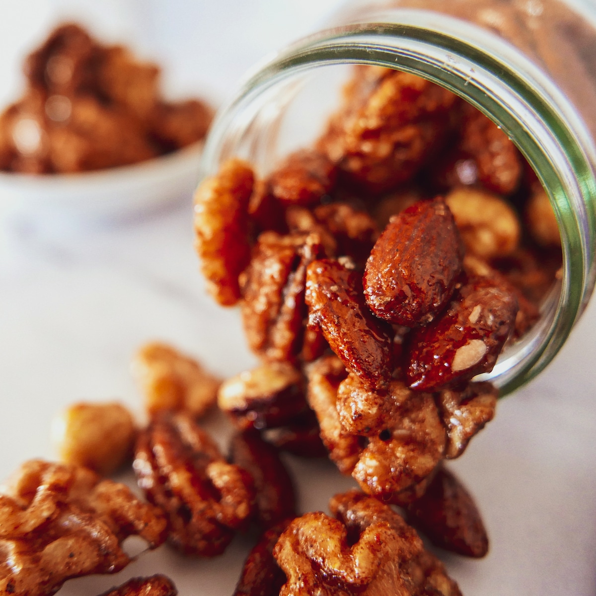 spiced-walnuts-and-almonds-in-a-glass-jar.jpg spiced walnuts, almonds, and pecans spilling out of a glass jar.