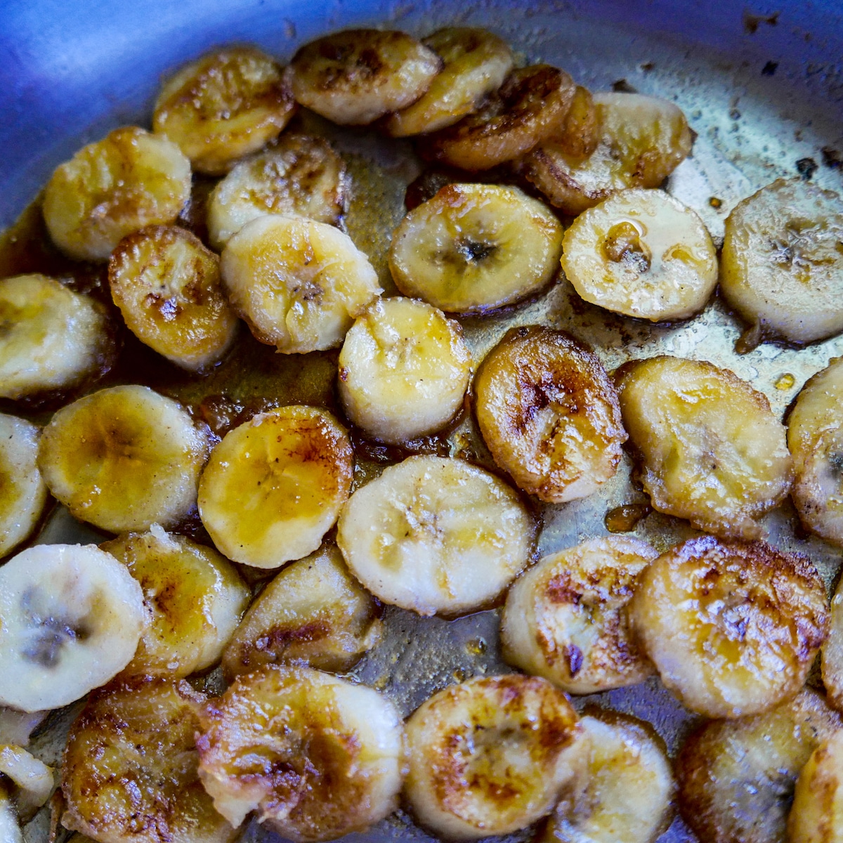 Banana slices being caramelized in a skillet.