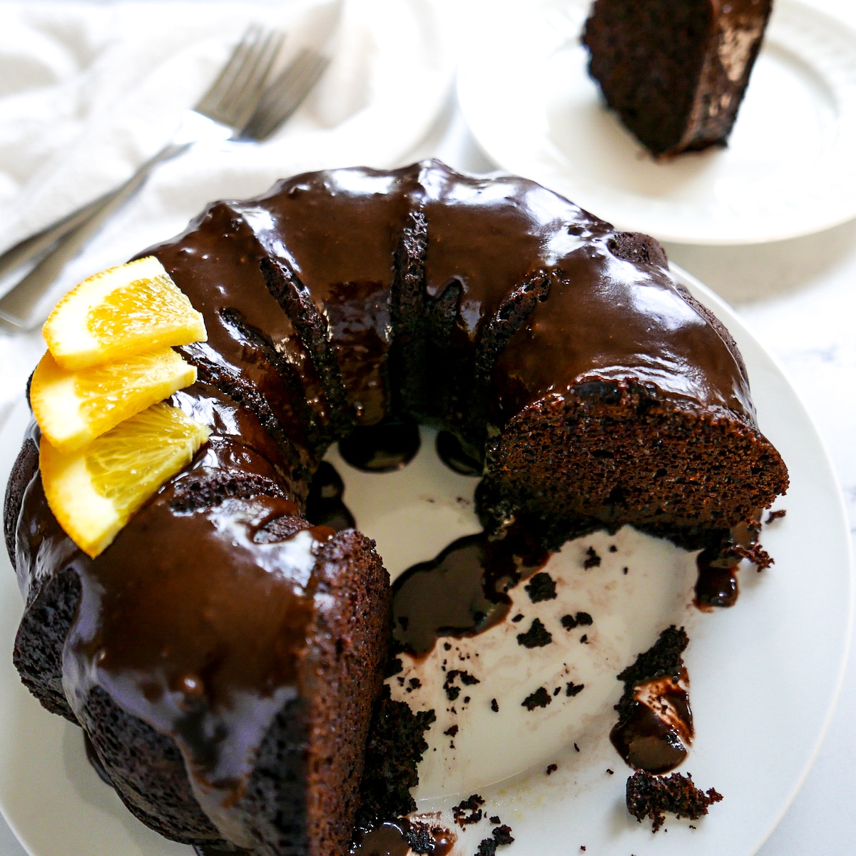 chocolate orange cake with slices cut out and a slice in the background.