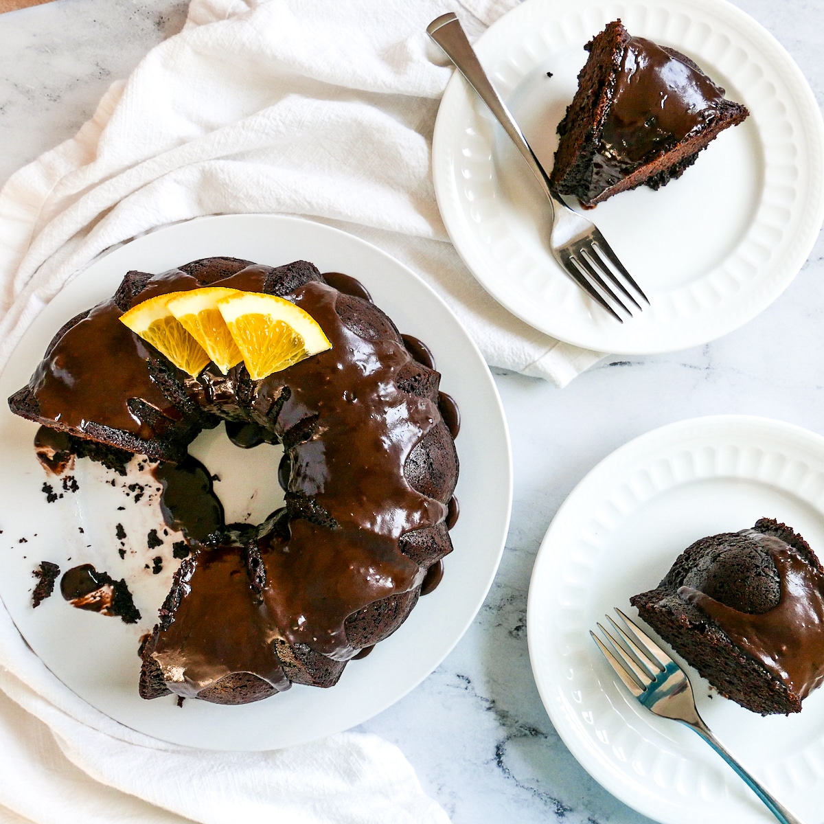 Half-eaten cake on a platter with two pieces on plates with forks.