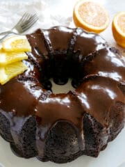 Chocolate orange cake with orange halves in background.