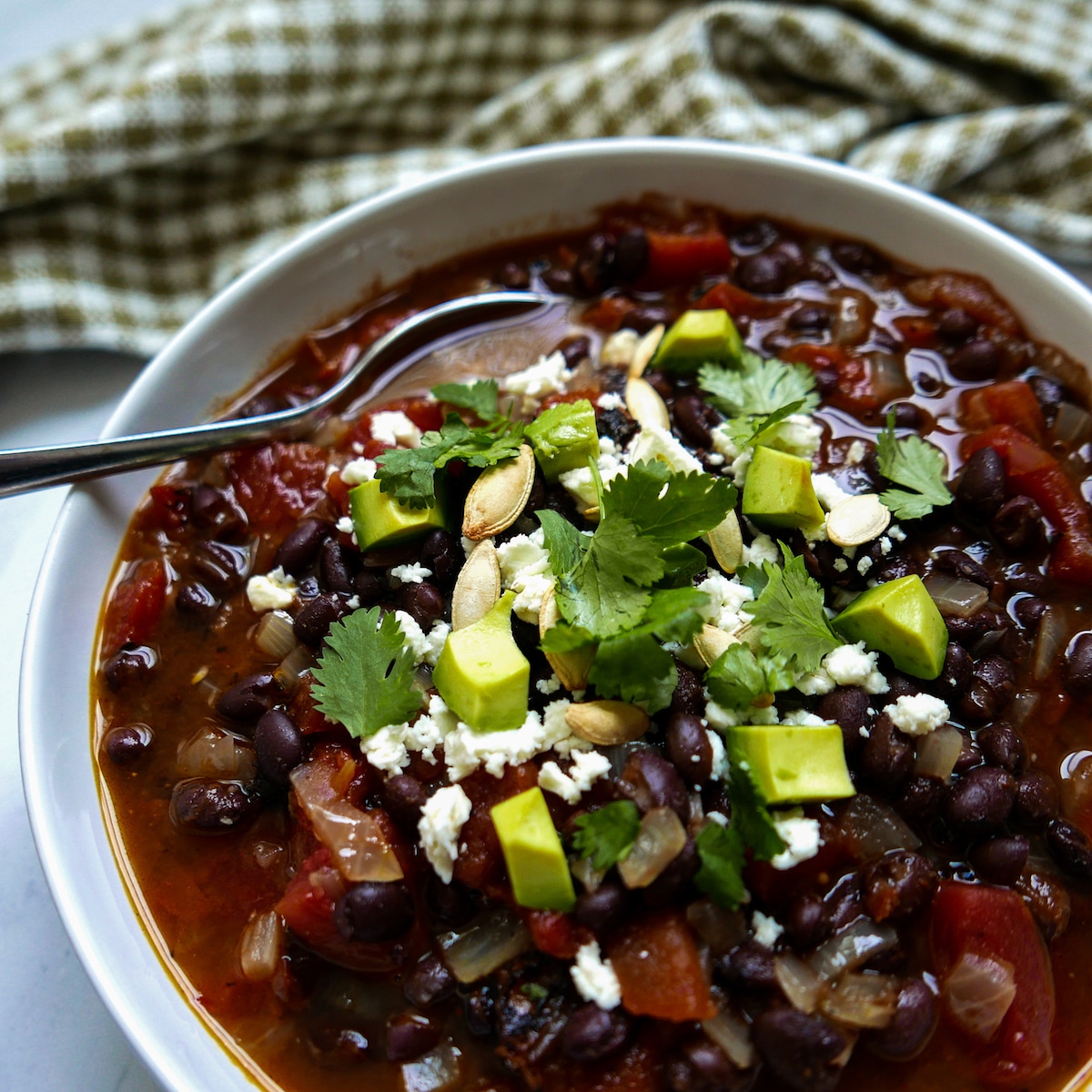 bowl of black bean soup garnished with cilantro and avocado.