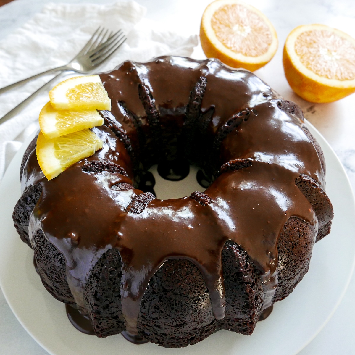 chocolate orange cake garnished with slices of orange and resting on a platter. 